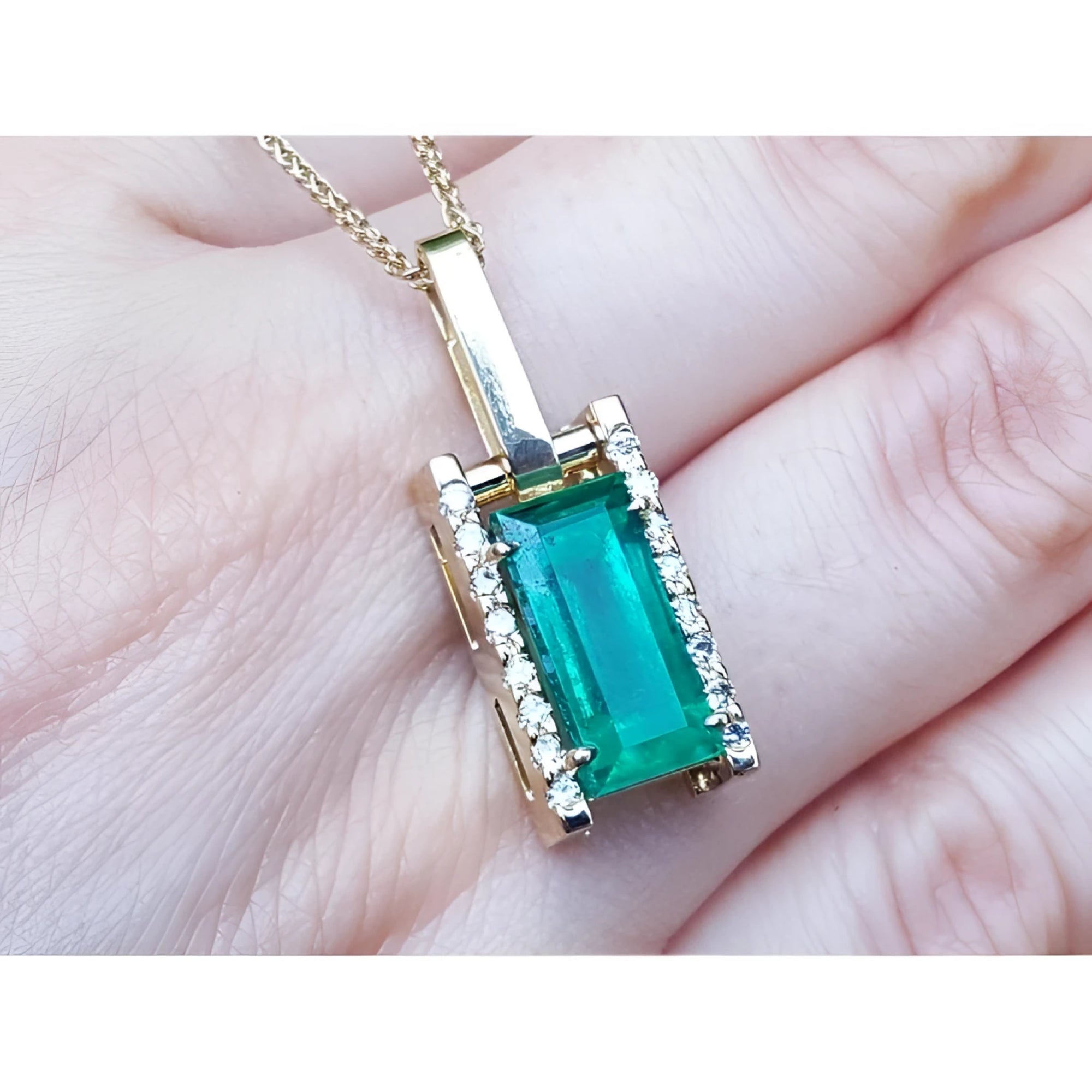 5.15 ct. baguette cut Colombian emerald pendant in 18K yellow gold with diamond accents.