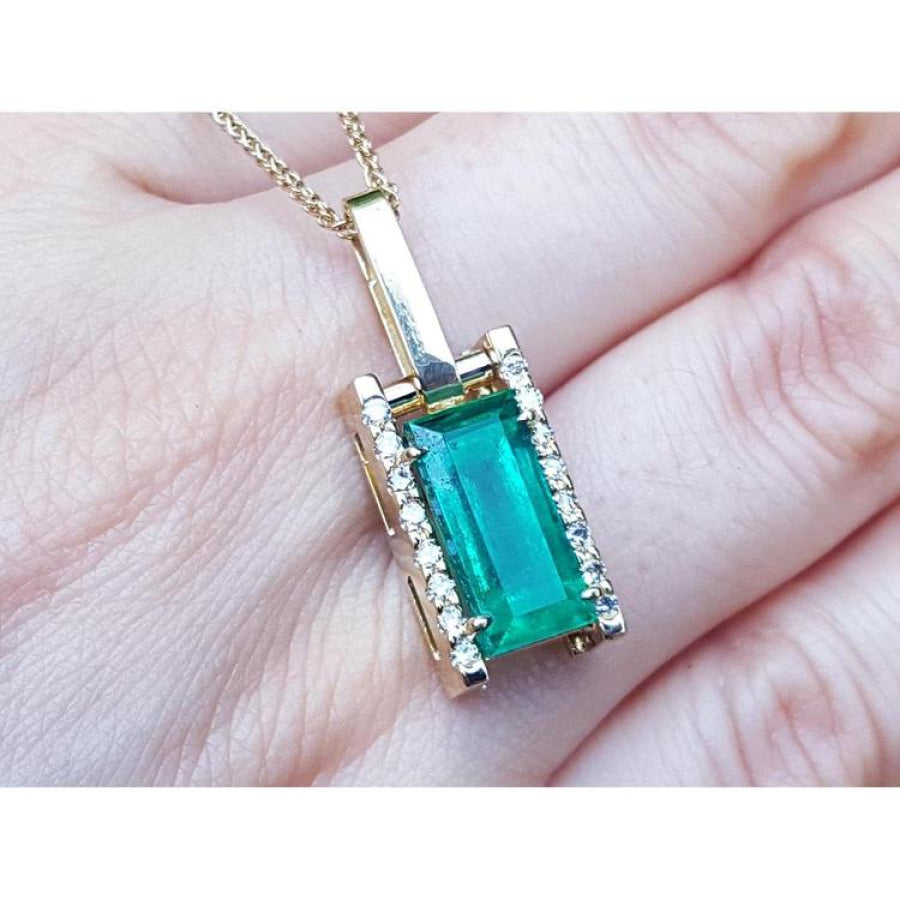 5.15 ct. baguette cut Colombian emerald pendant in 18K yellow gold with diamond accents.