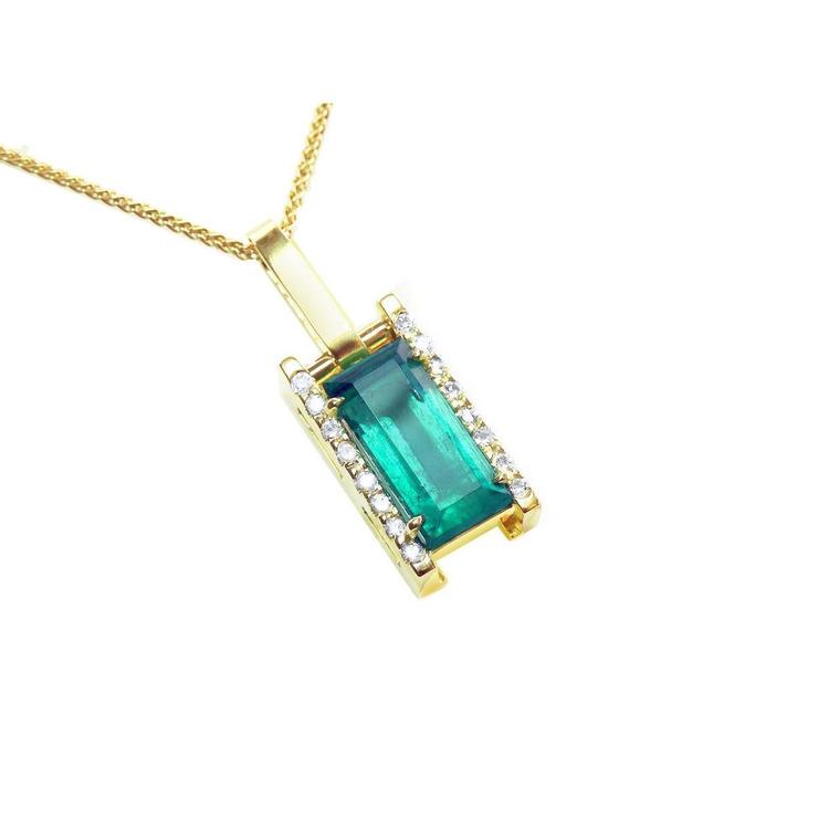 A yellow gold baguette cut emerald pendant with diamond accents topside view.