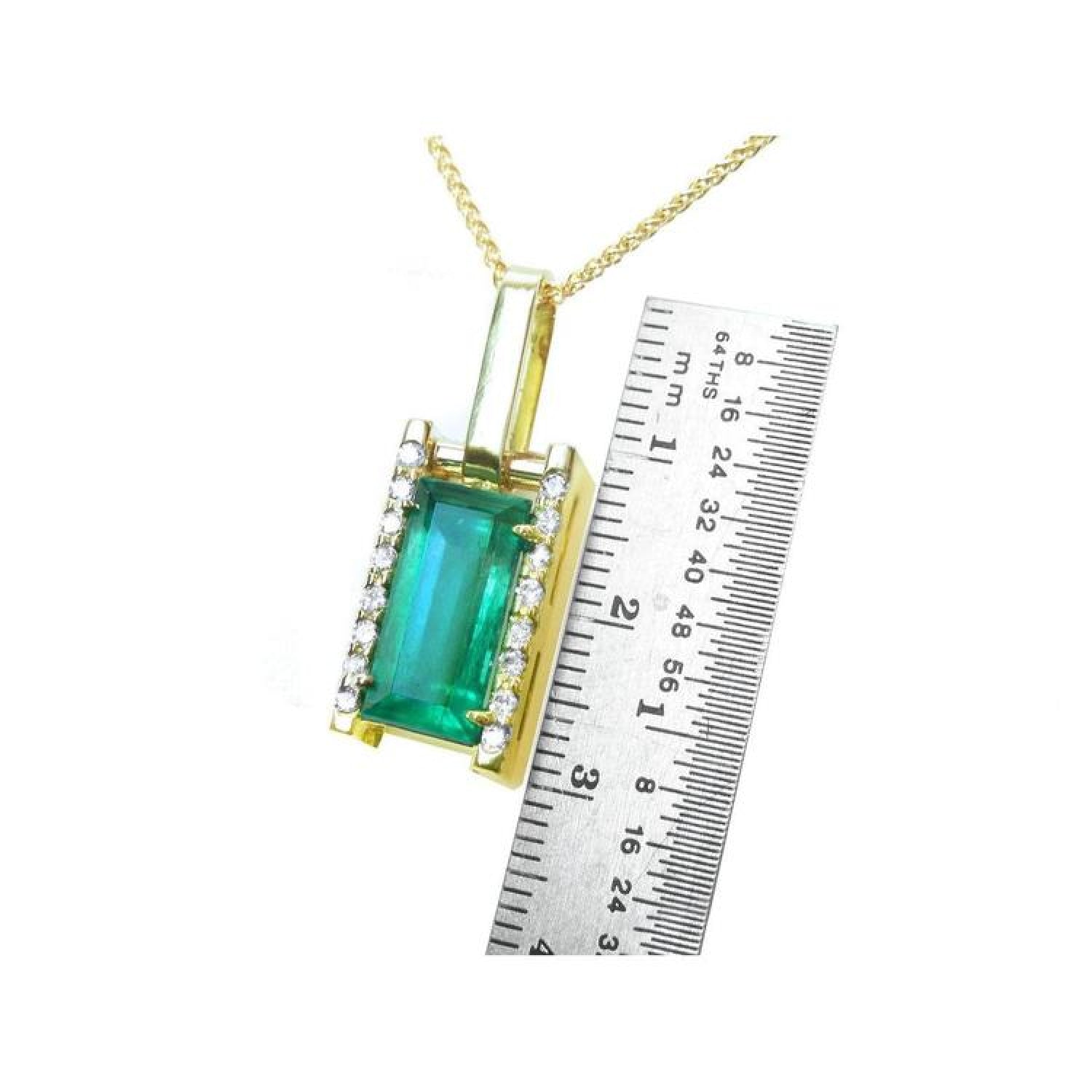 Baguette cut emerald pendant in 18K yellow gold with diamond accents, shown next to a ruler.