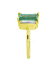 A yellow gold natural emerald and side baguette diamond ring displaying the side profile top and band view.