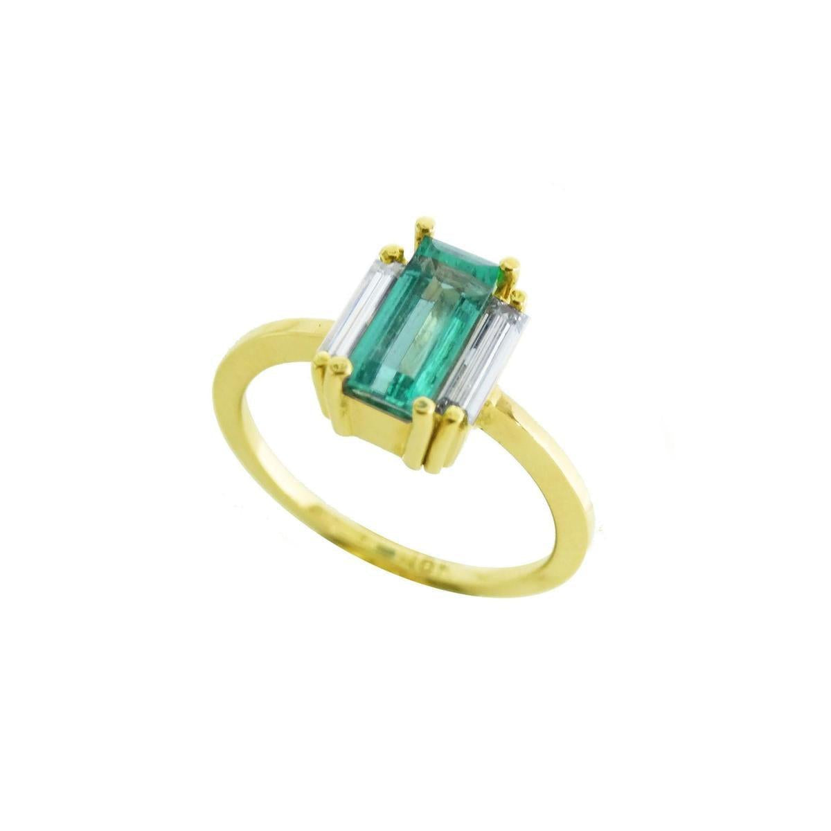 A 18k yellow gold emerald baguette cut ring with side diamonds on a white background.
