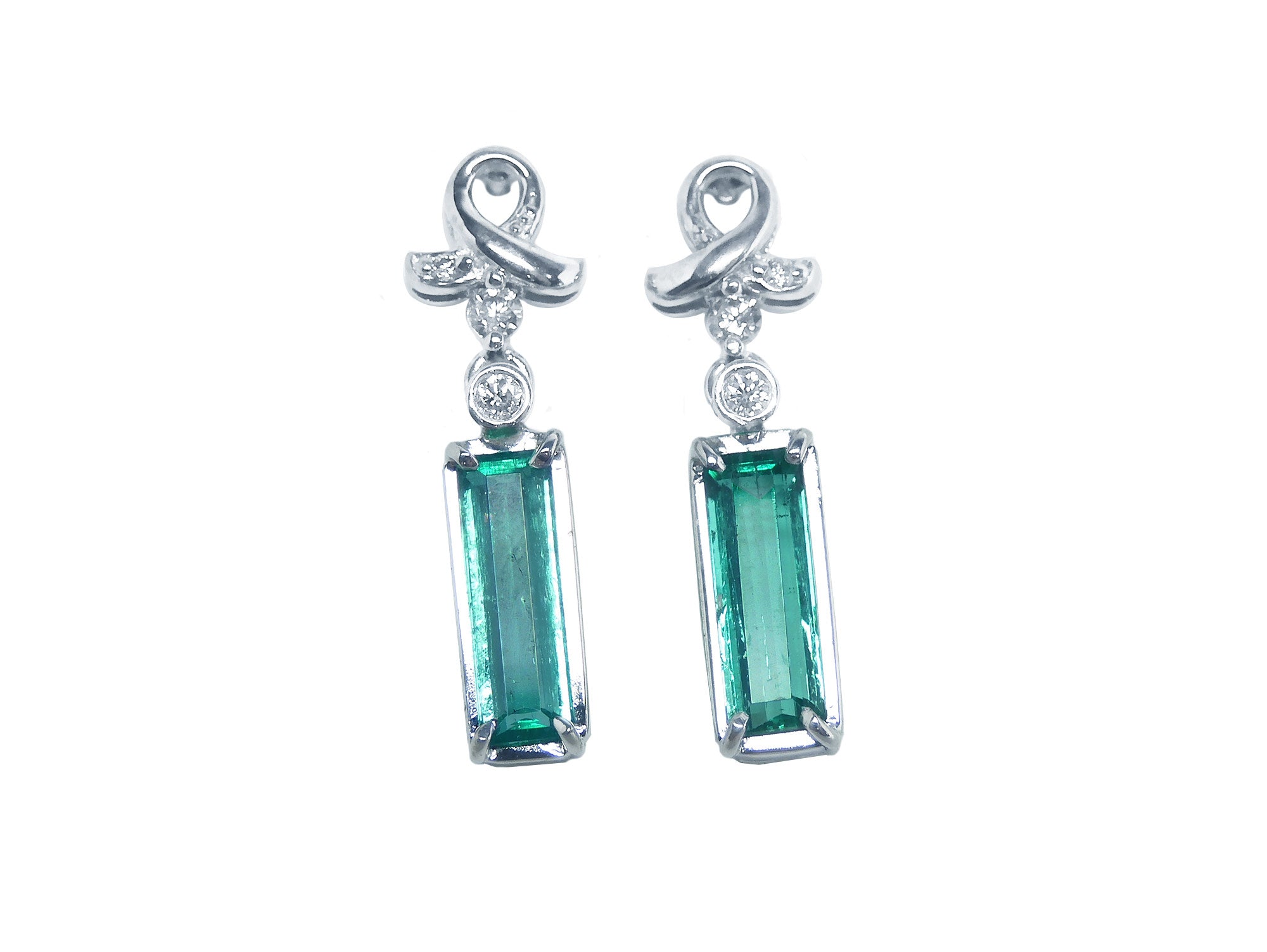 Pair of emerald baguette cut earrings with ribbon-like hooks on a front position full top view.