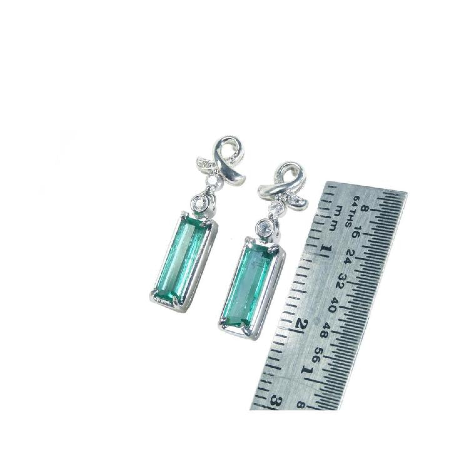 Emerald-cut 1.89 ct. natural emerald earrings in 14k white gold with ribbon design and accent diamonds.