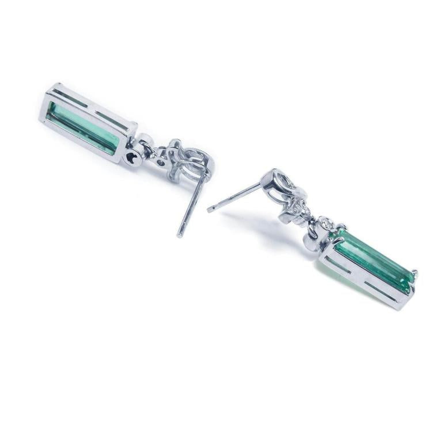 Emerald-cut natural emerald earrings in 14k white gold with ribbon design and accent diamonds.