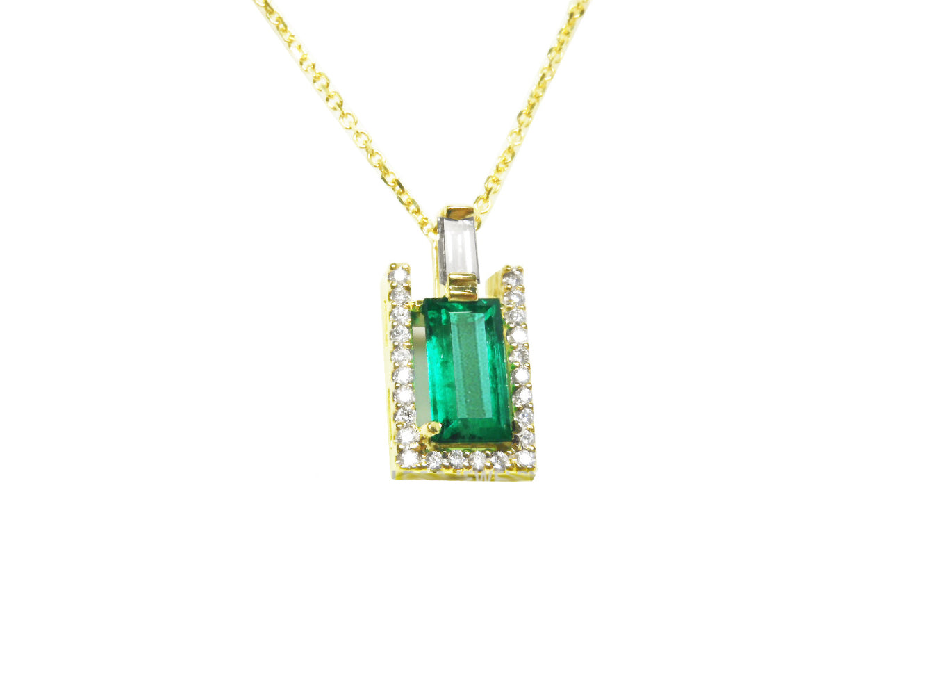 The topside view of a natural emerald baguette cut surrounded of diamonds pendant on a yellow gold chain.