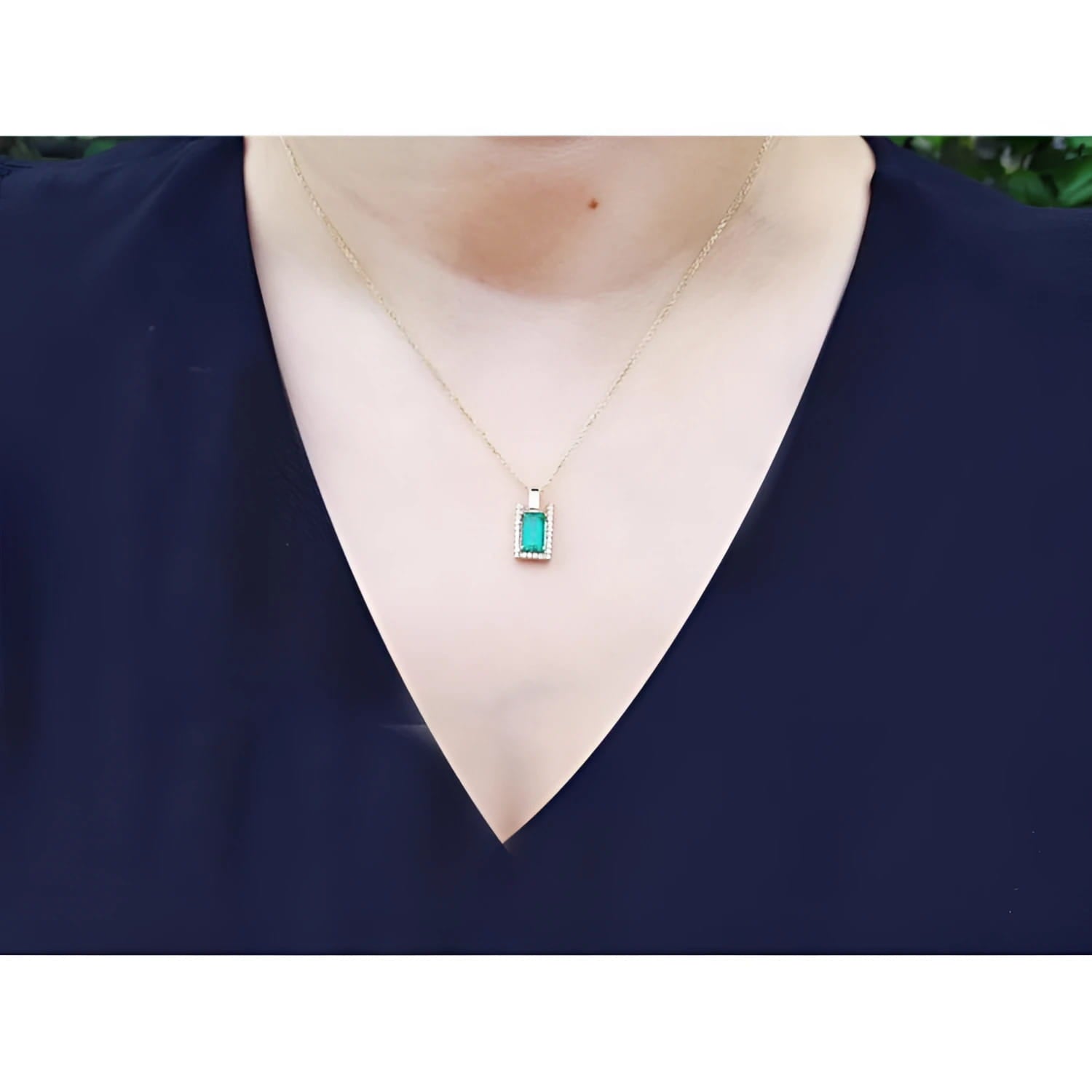 Baguette cut emerald pendant necklace with natural diamonds in 14K yellow gold on a model.