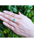 1.14 ct baguette emerald pendant necklace with diamond bail on a woman's hand, 14K yellow gold.