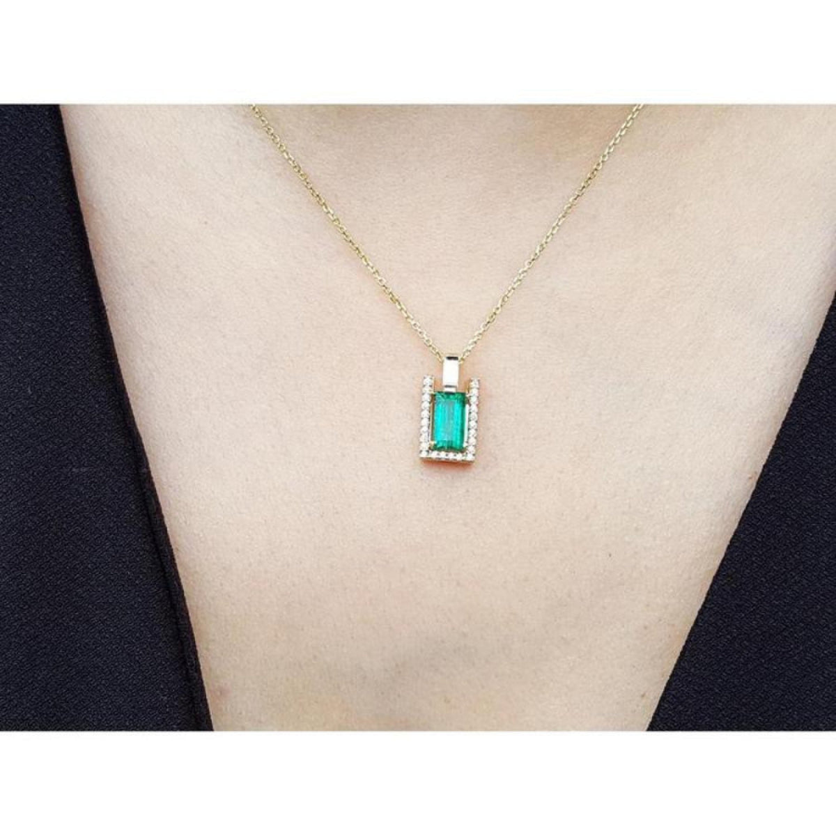Baguette emerald and diamond pendant necklace in 14K yellow gold, worn on a neck.