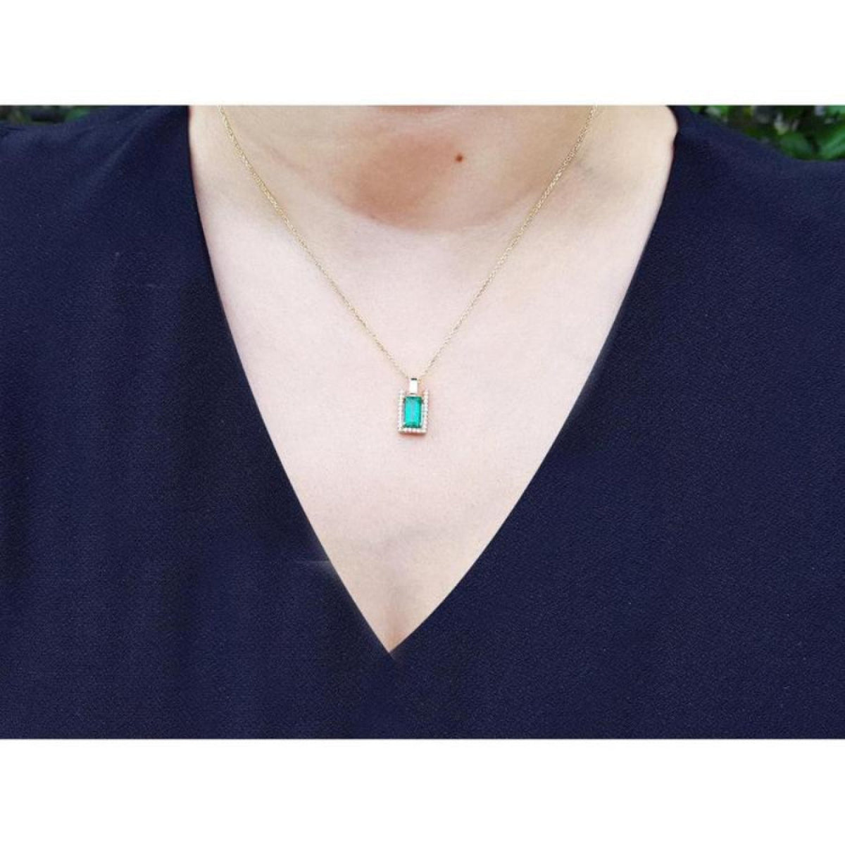 Baguette cut emerald pendant necklace with natural diamonds in 14K yellow gold on a model.