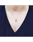 Baguette cut emerald pendant necklace with natural diamonds in 14K yellow gold on a model.