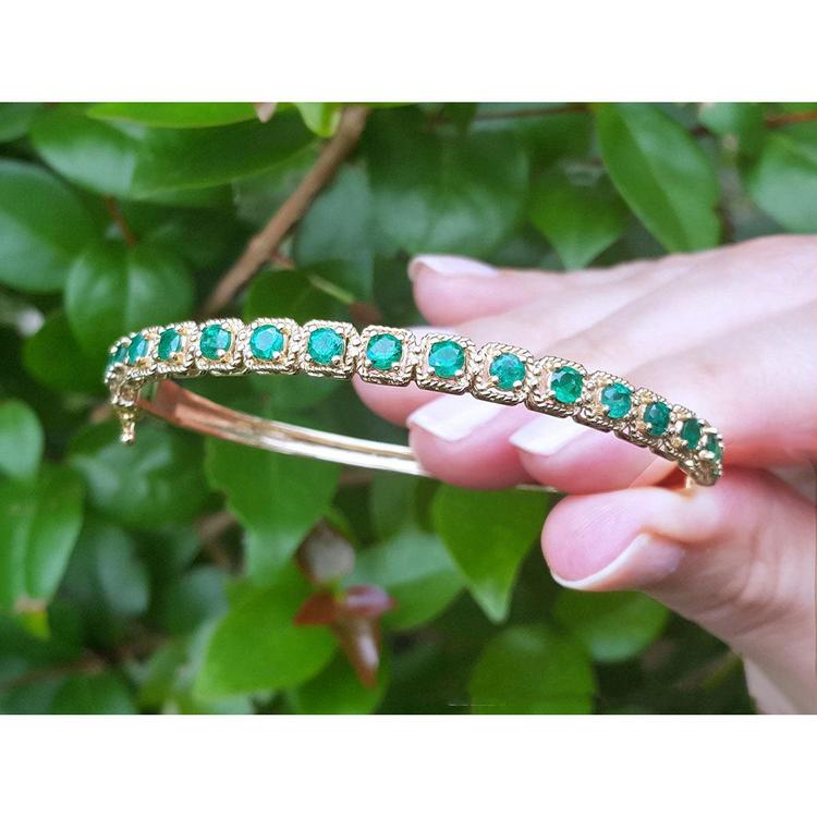14K gold bangle bracelet with round bluish-green emeralds in square links with rope borders.