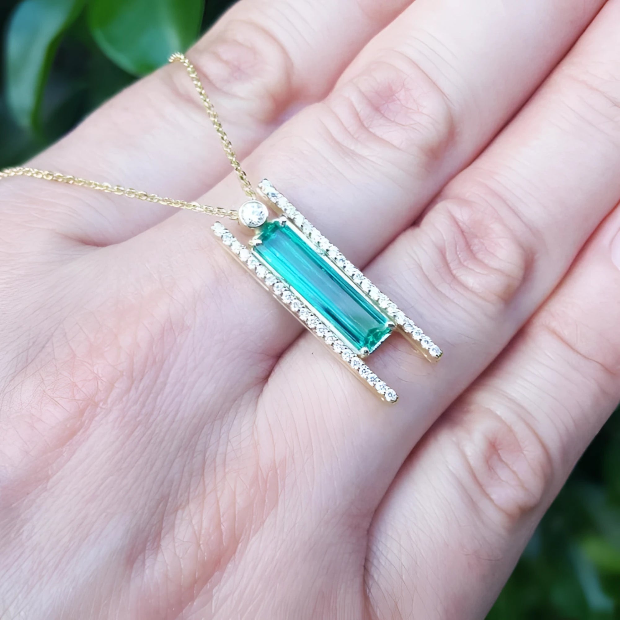 Emerald baguette cut necklace with natural diamonds, 14K yellow gold, and sliding tube bail chain.