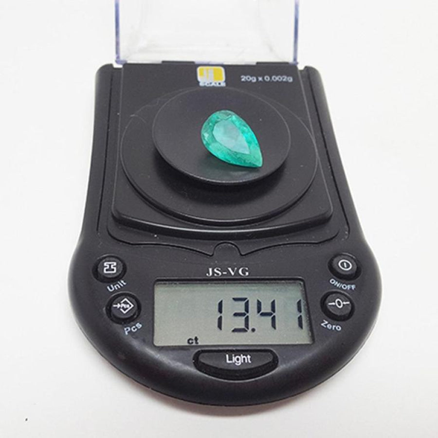 13.42 ct pear-cut Colombian emerald, medium green, on a digital scale displaying its carat weight.