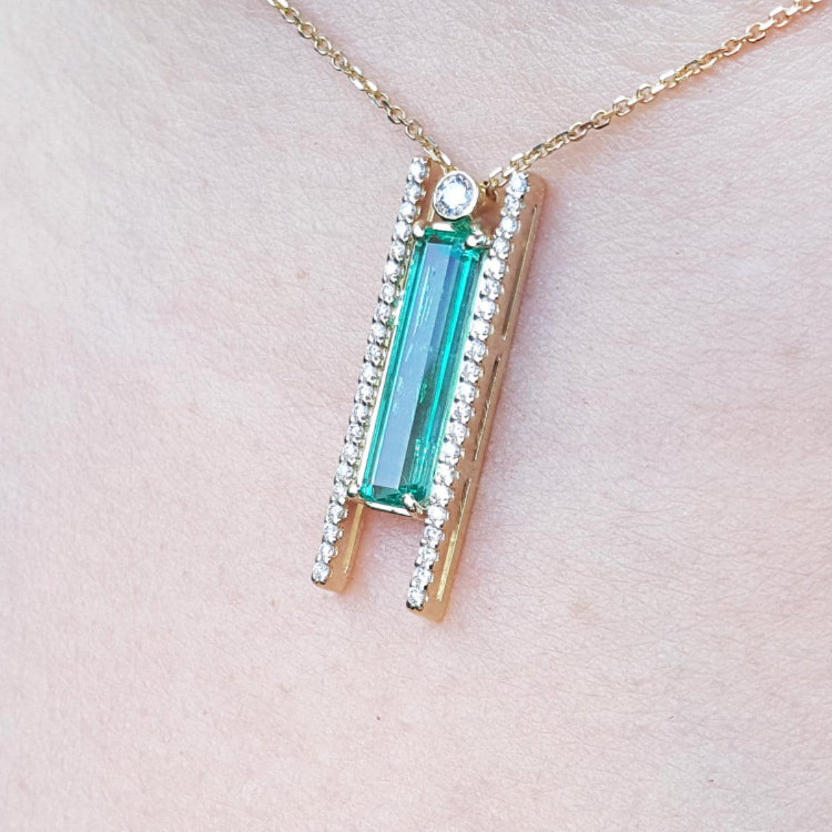 lady&#39;s gold emerald and diamond necklace with a green gemstone pendant on a woman&#39;s collar