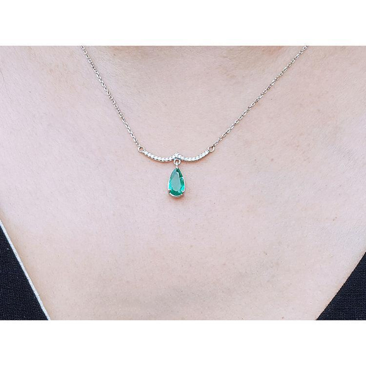 14K white gold necklace with a pear-shaped Colombian emerald and diamond-studded wavy bar.