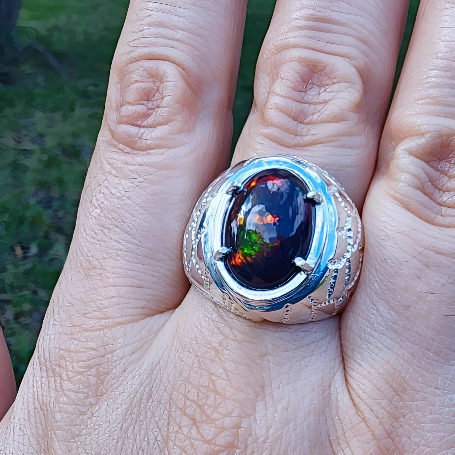 Men's black Ethiopian opal ring in sterling silver, featuring red-orange and blue hues.