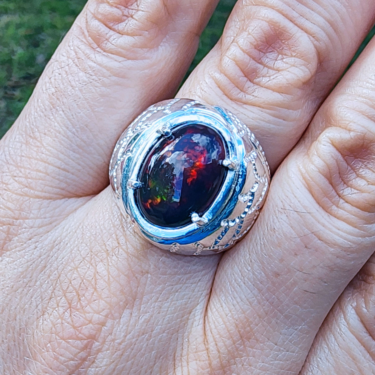 Silver ring for men with a colorful Ethiopian black opal on a person's finger