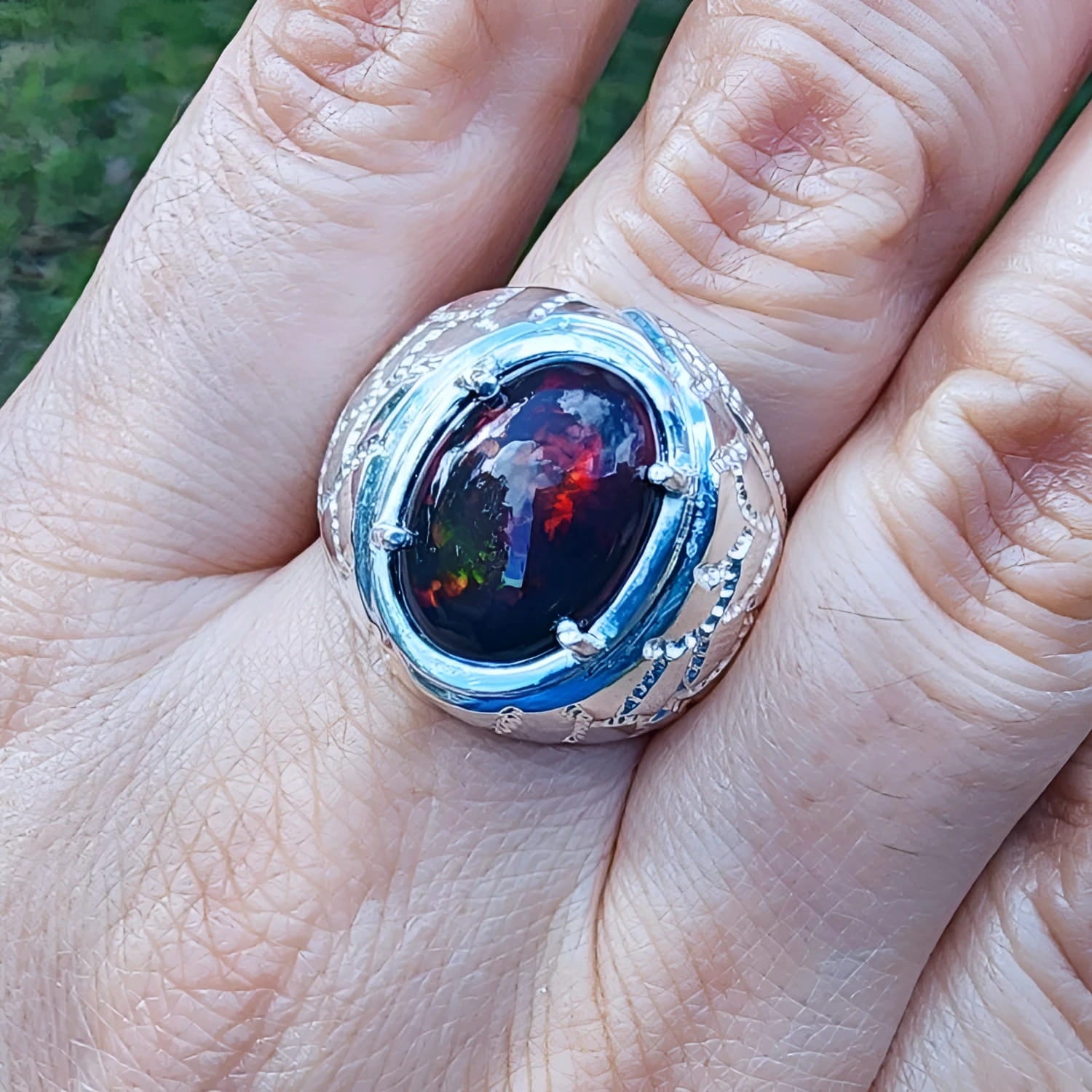 Men's black Ethiopian opal ring with red-orange and blue hues, set in ornate sterling silver.