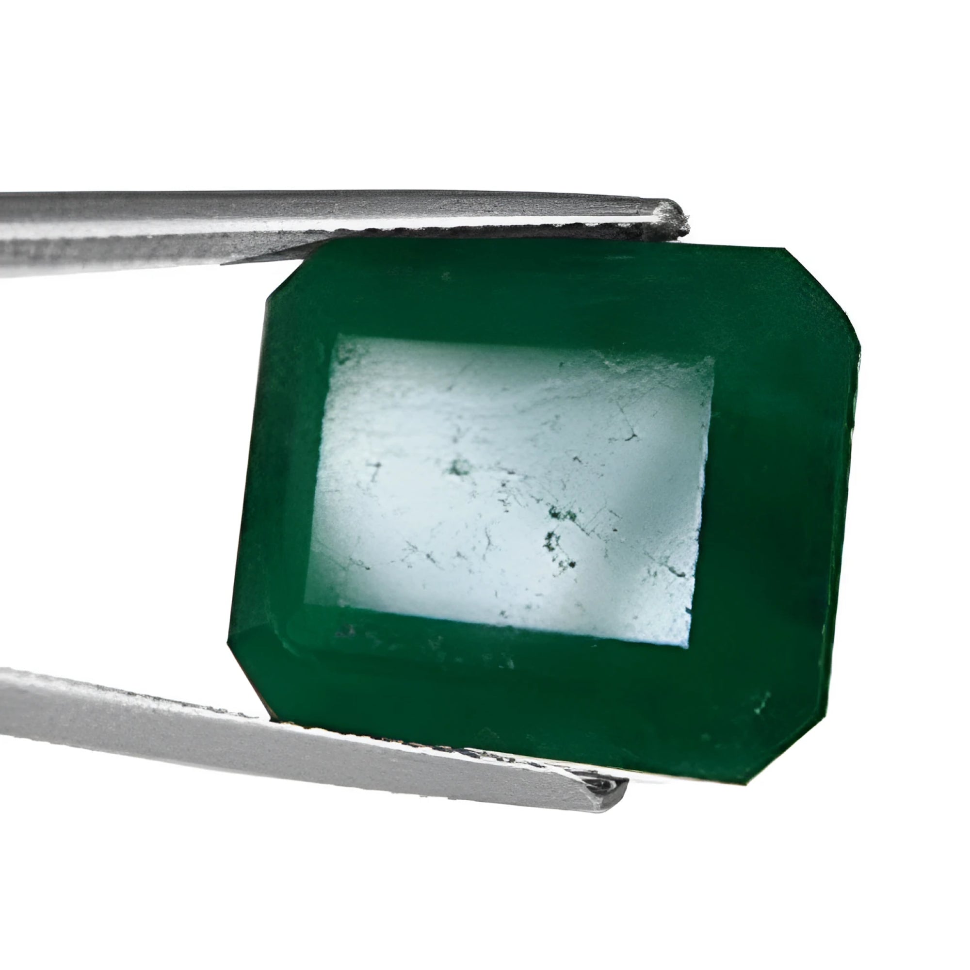 Emerald with filled pits on the table between tweezers.