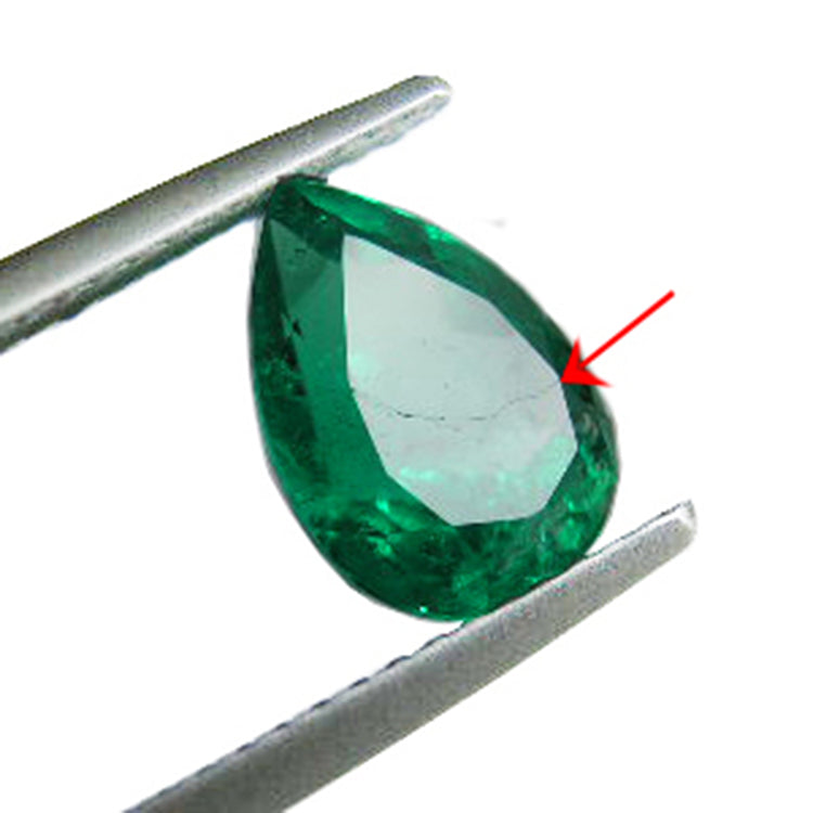 Teardrop-shaped emerald held by tweezers with a red arrow pointing to a synthetic filled fracture.