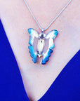 Butterfly-shaped pendant necklace on a person's neck against a blue background
