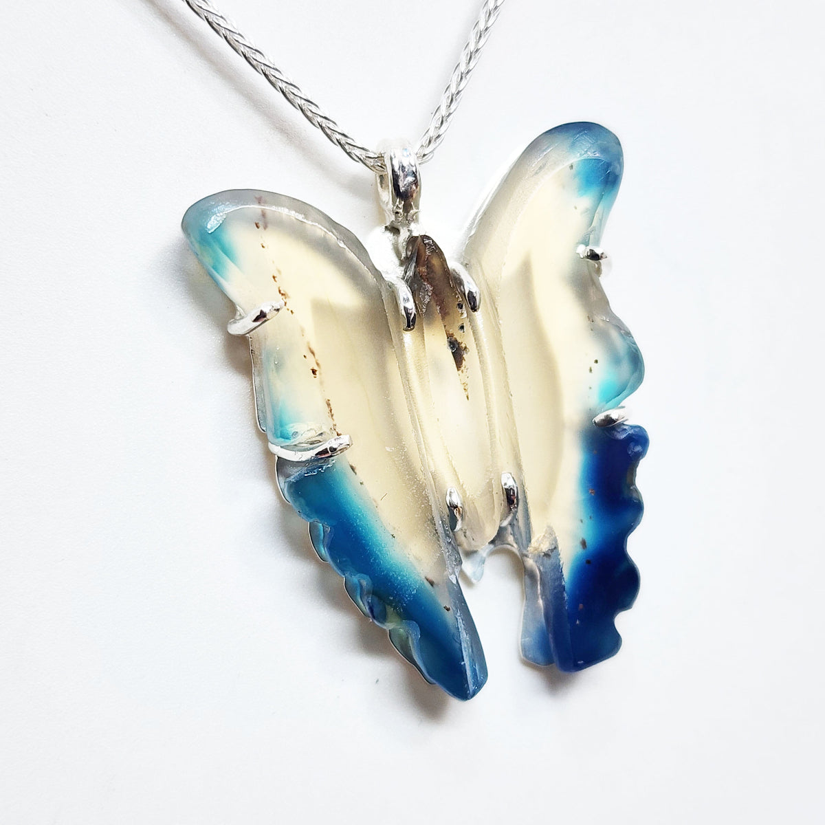 Butterfly-shaped pendant with blue and white wings on a white background