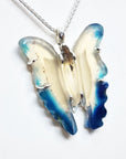 Butterfly-shaped pendant with blue and white wings on a white background