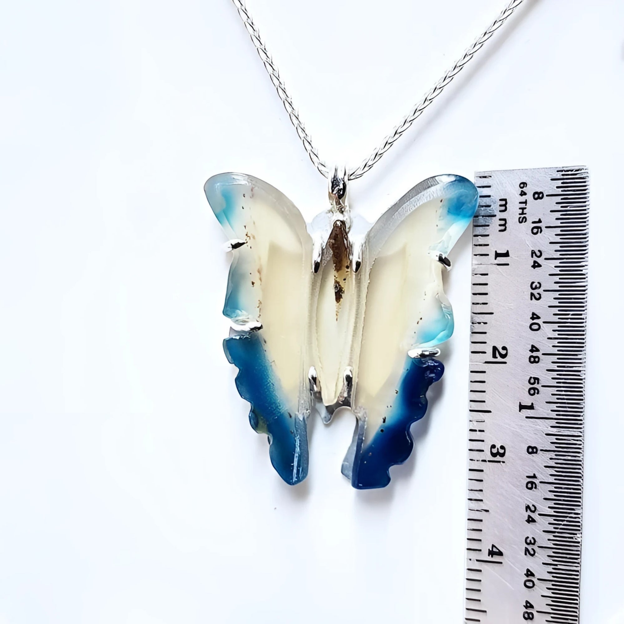 Hand-carved blue agate butterfly pendant with sterling silver frame, shown next to a ruler for size.