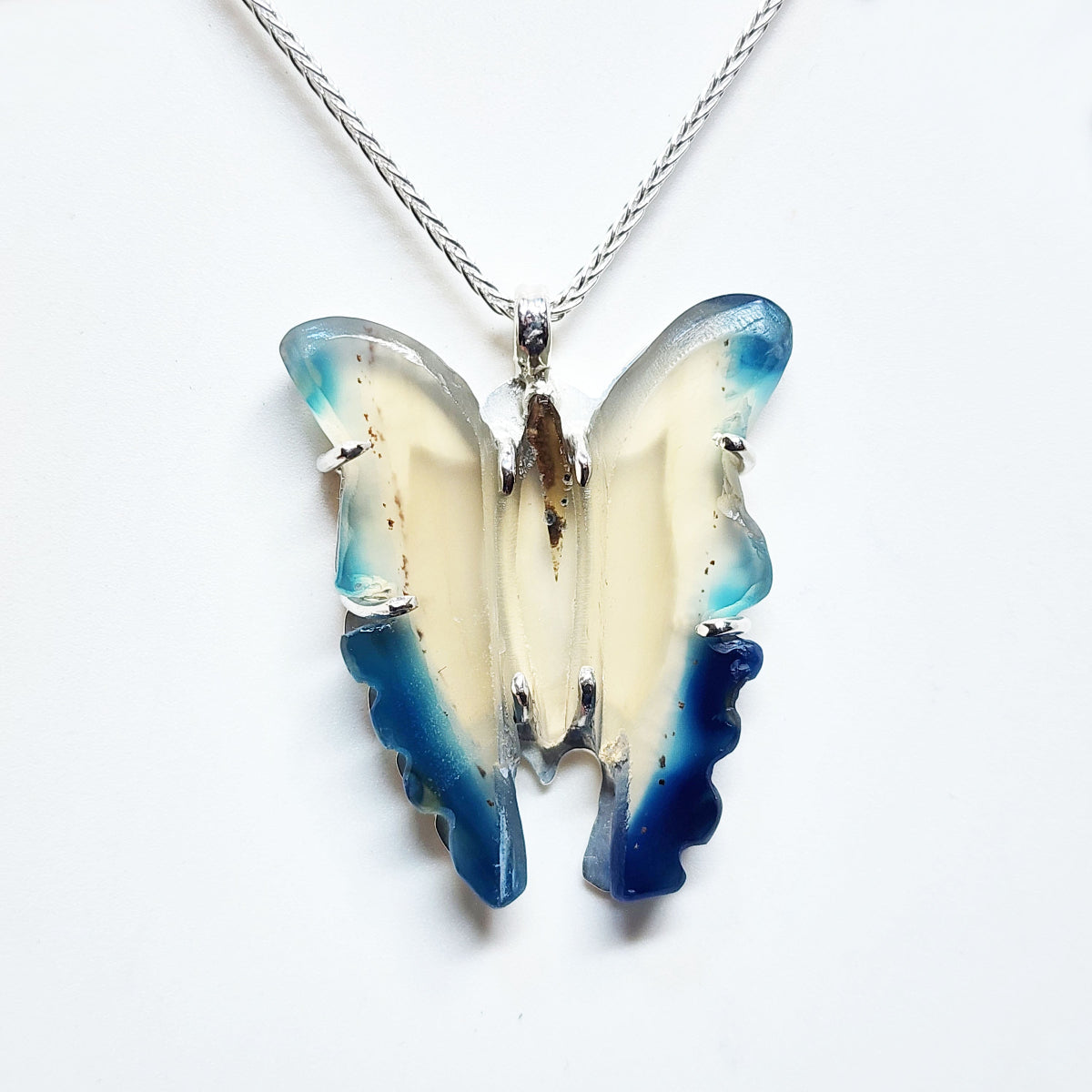 Butterfly-shaped pendant on a chain against a white background
