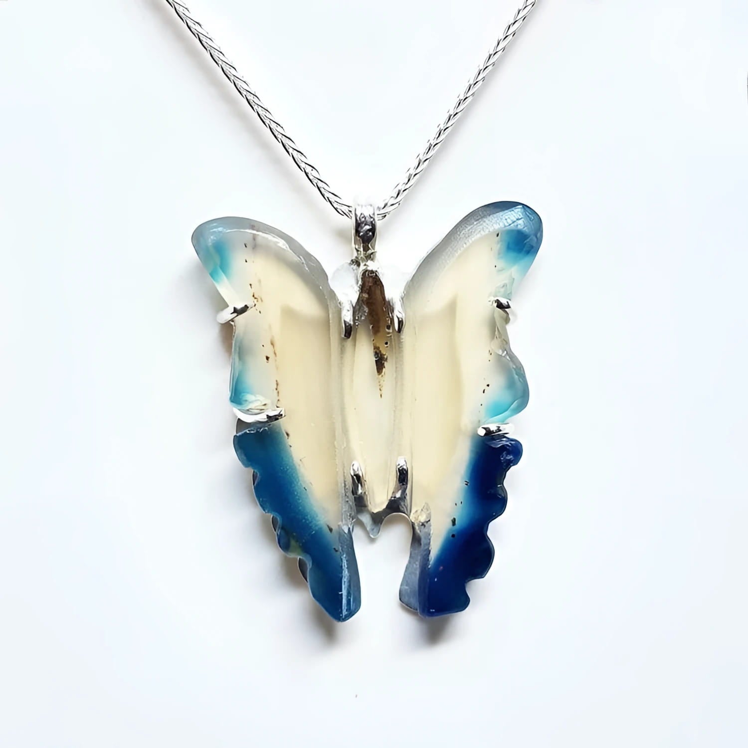 Hand-carved blue agate butterfly pendant with cream body and blue wings, set in sterling silver.