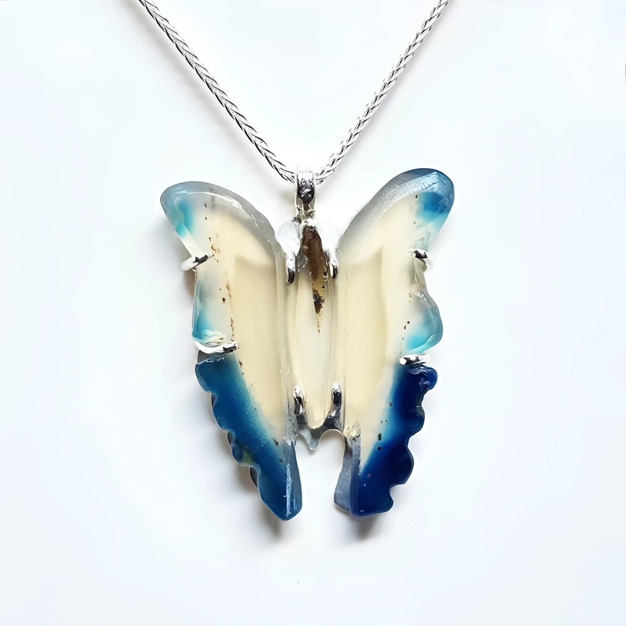 Hand-carved blue agate butterfly pendant with cream body and blue wings, set in sterling silver.