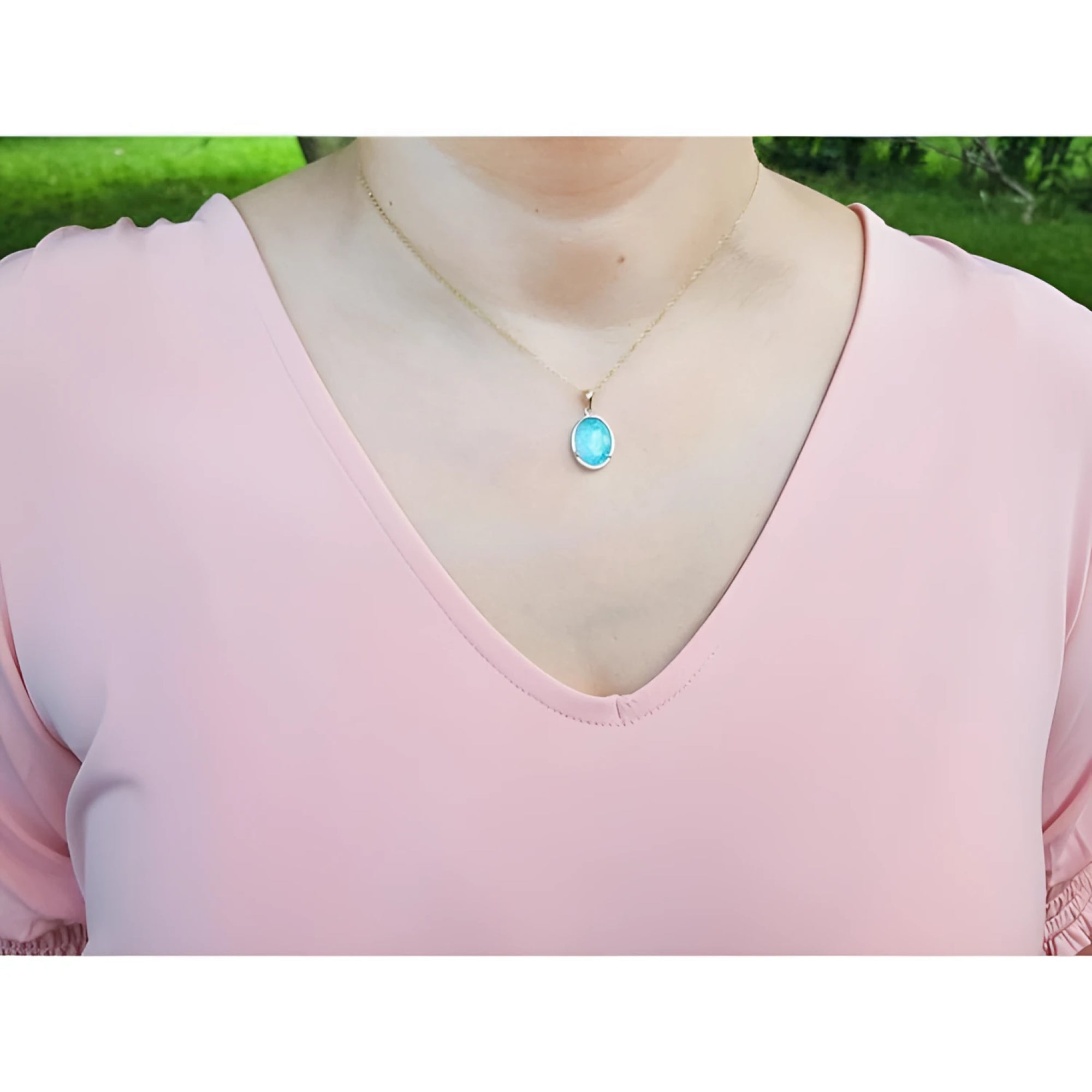 Oval blue-green opal pendant in 14K yellow gold on a woman's neck.