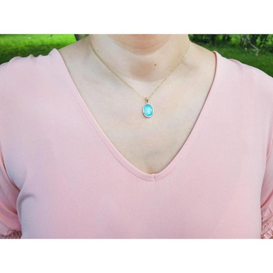 Oval blue-green opal pendant in 14K yellow gold on a woman's neck.