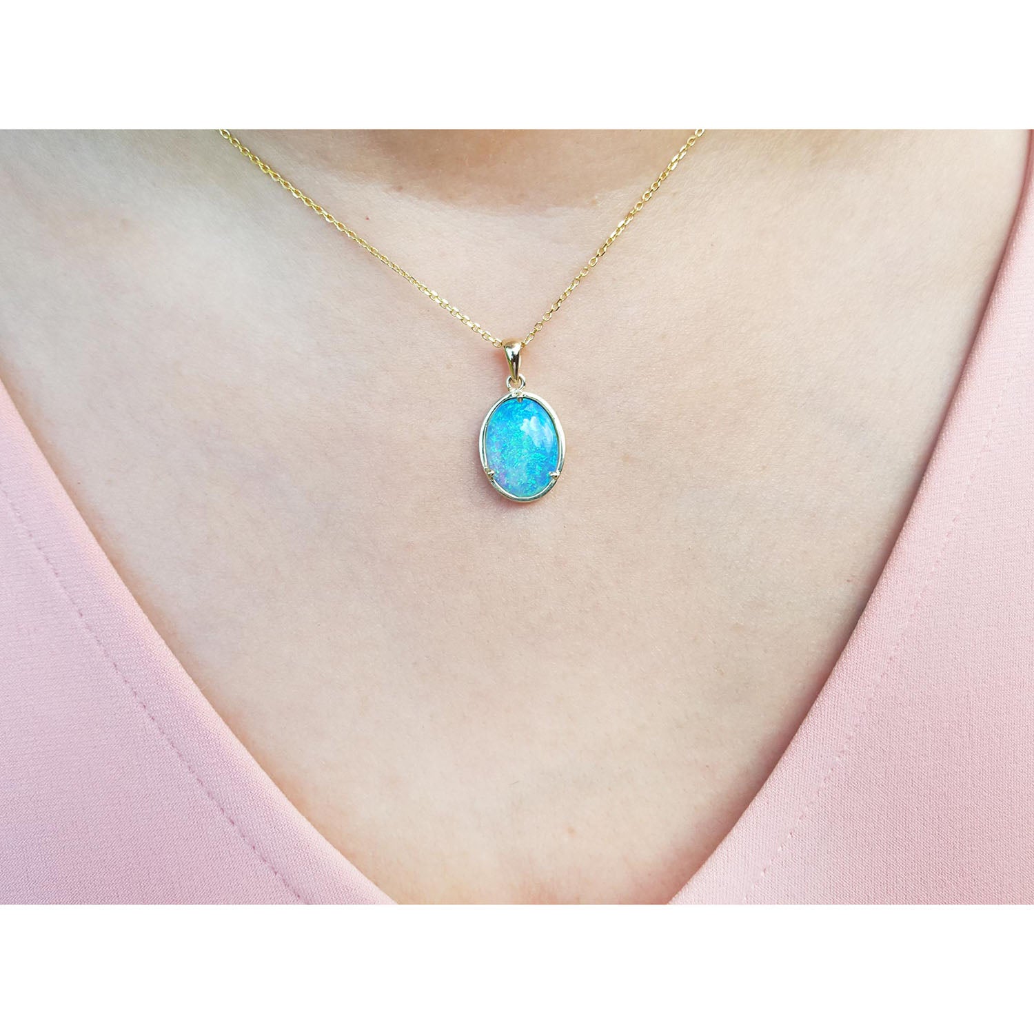 Necklace with a blue opal pendant on a person&#39;s neck wearing a pink top