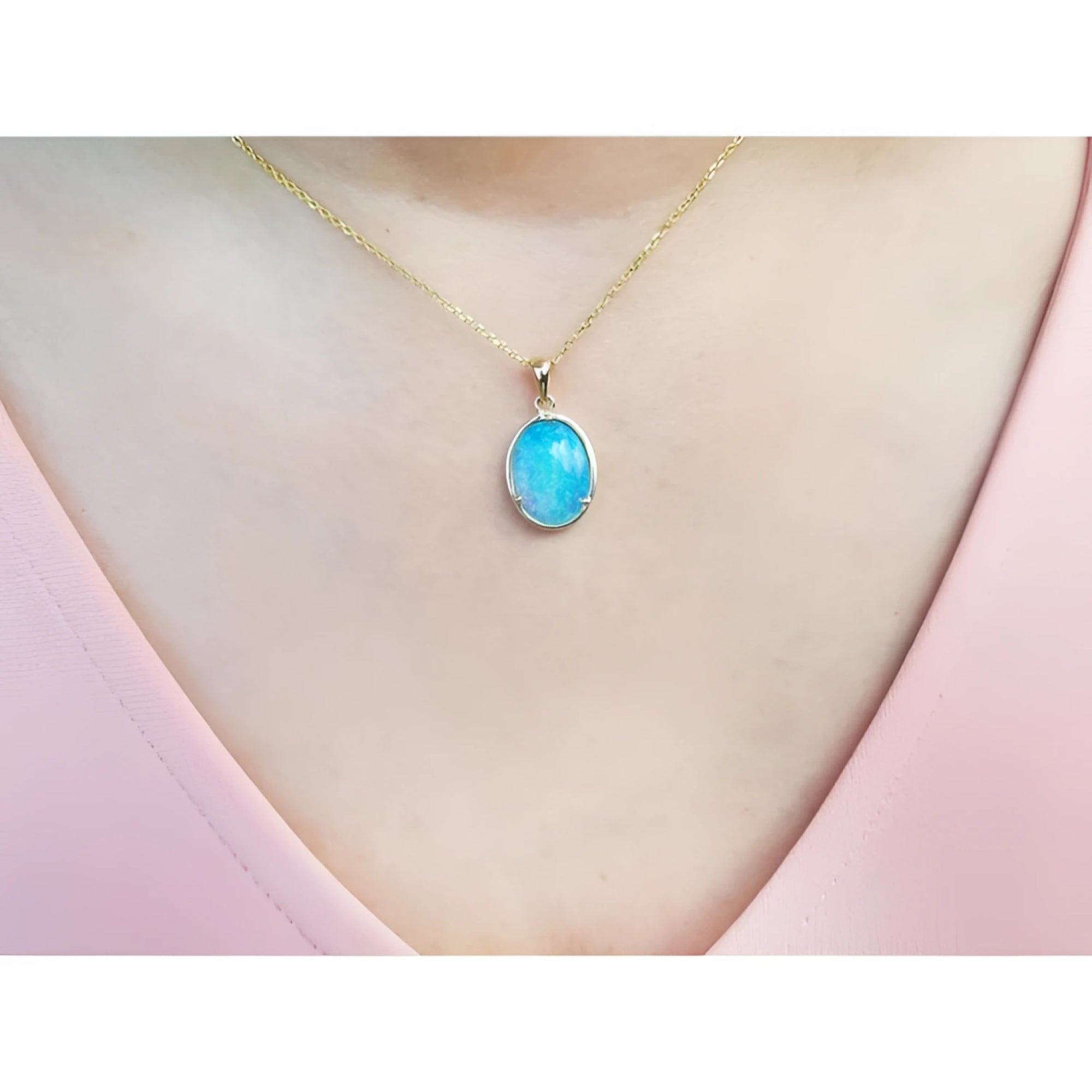 Oval Australian opal pendant with blue-green sparks on a 14K yellow gold chain.