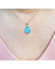 Necklace with a blue opal pendant on a person's neck wearing a pink top