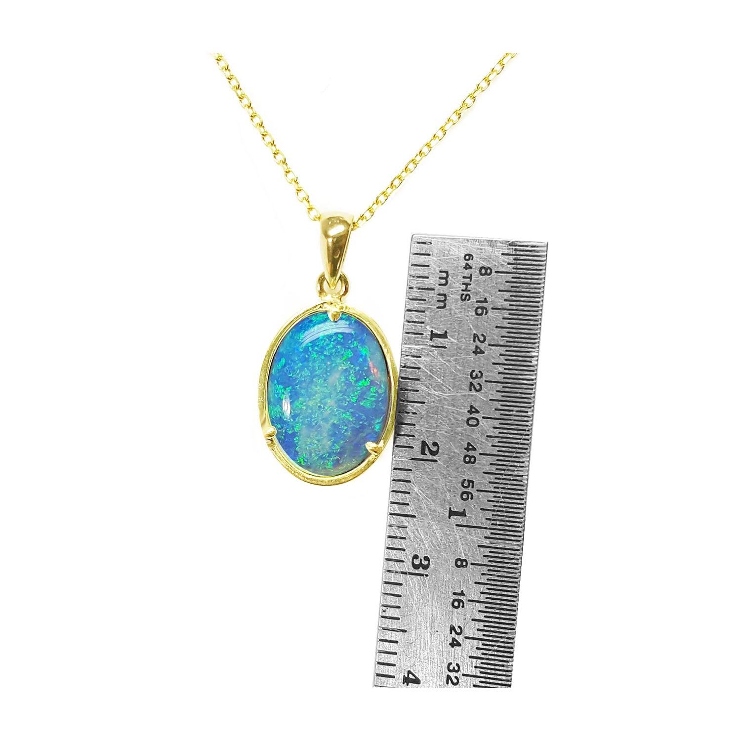 Opal pendant necklace with gold chain next to a ruler for scale on a white background
