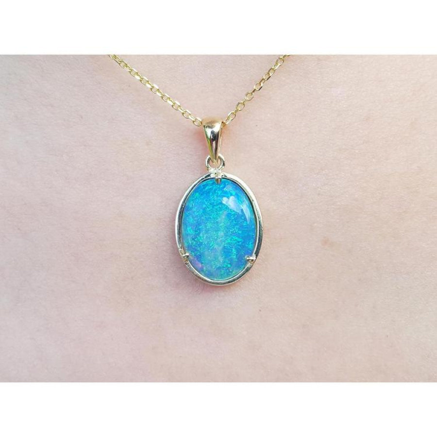 Oval blue-green opal pendant in 14K yellow gold on a delicate chain, worn on skin.