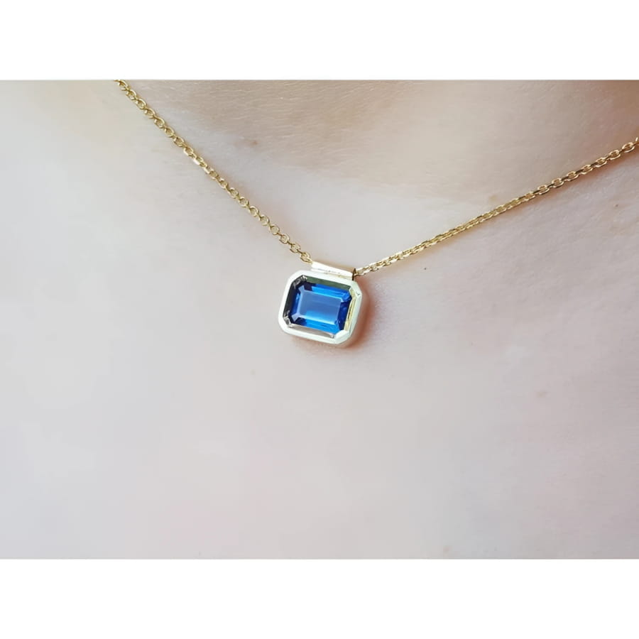 1.01 carat medium-dark blue sapphire choker necklace, bezel set in 14K gold on a cable chain.