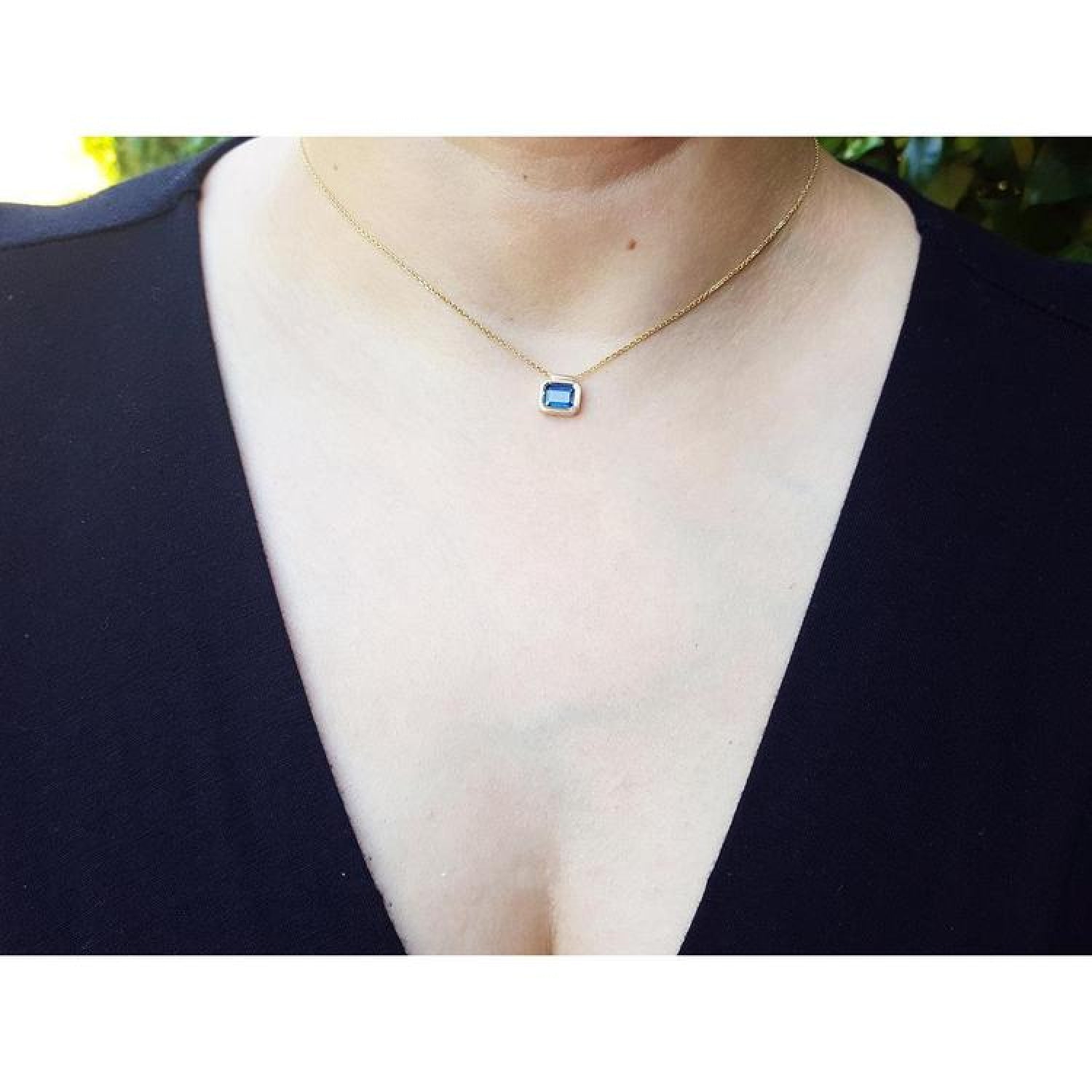 1.01 ct blue sapphire bezel set on a 14K gold cable chain choker necklace worn by a woman.
