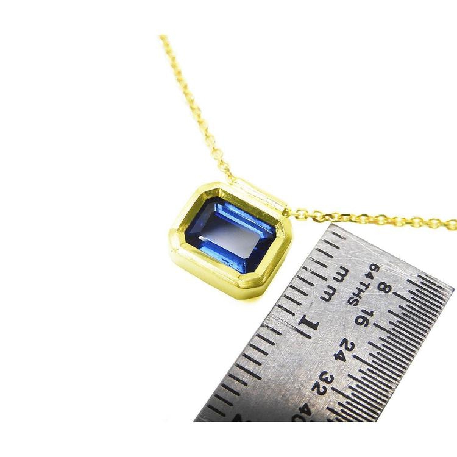 1.01 ct blue sapphire choker in a bezel setting on a 14K gold cable chain, next to a ruler.