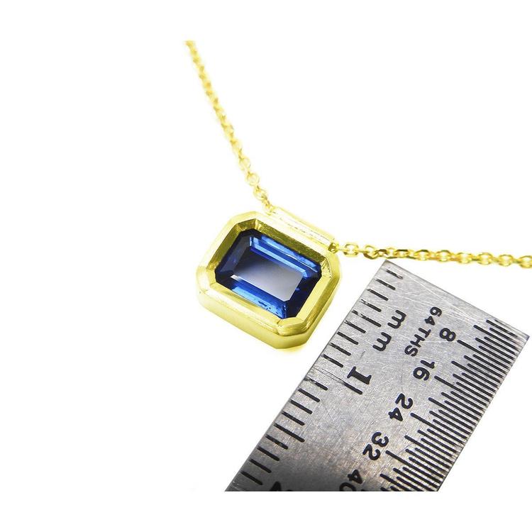 1.01 ct blue sapphire choker in a bezel setting on a 14K gold cable chain, next to a ruler.