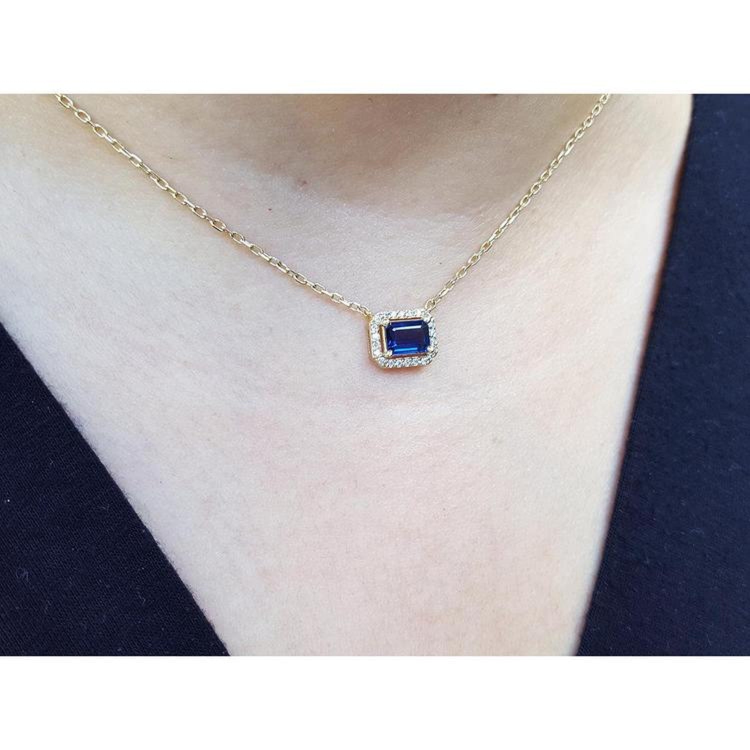 1.03 ct. emerald-cut blue sapphire necklace with diamond halo on a 14K yellow gold chain.