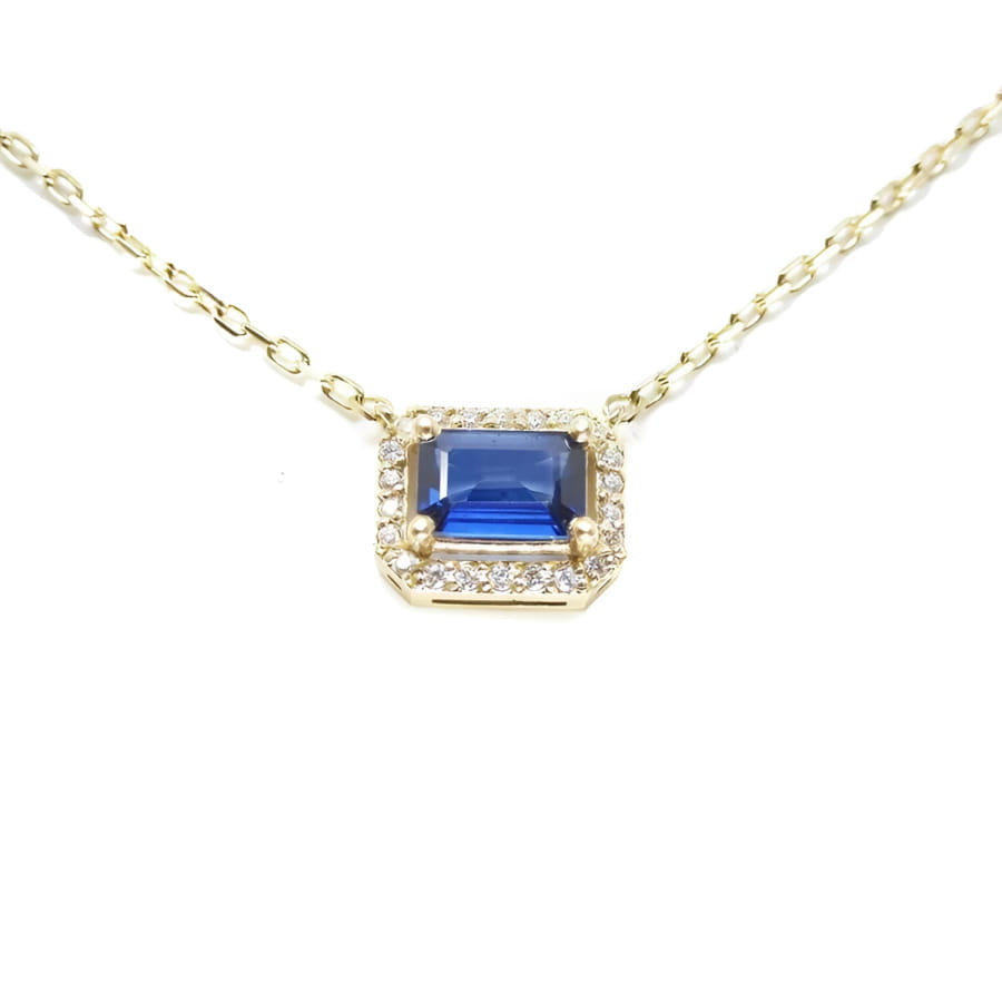 14K yellow gold necklace with an east-west emerald cut blue sapphire surrounded by diamonds.