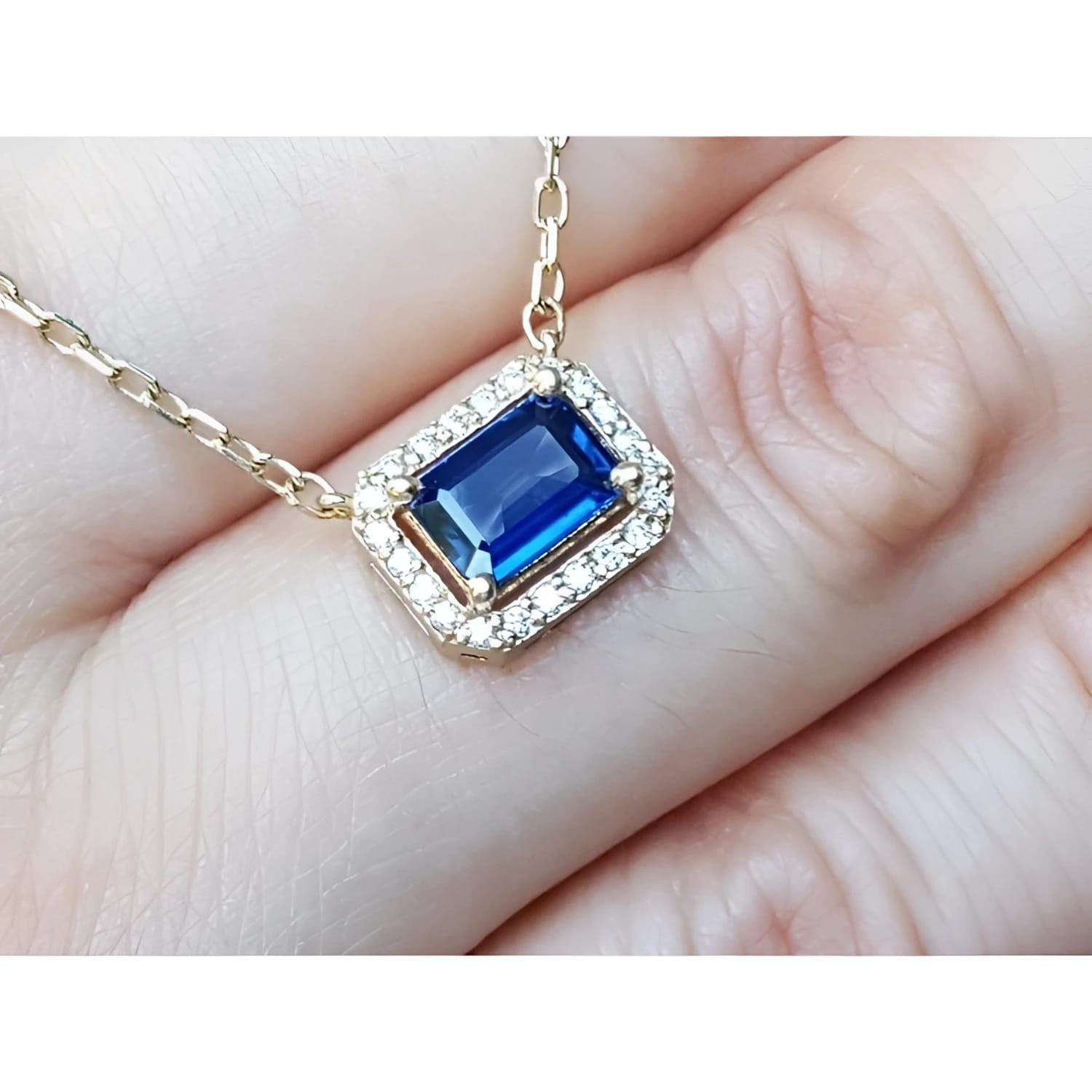 Blue sapphire necklace emerald cut in alo of natural diamonds set in 14k yellow gold.