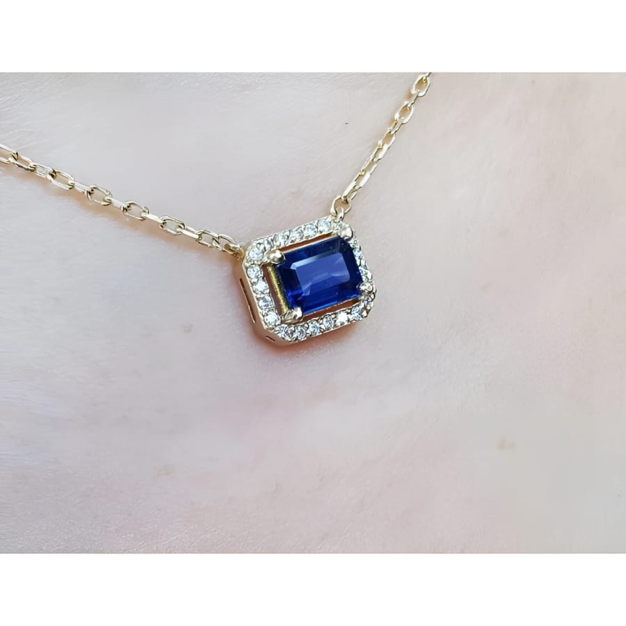 1.03 ct. natural blue sapphire, emerald cut, east-west necklace with diamond halo in 14K yellow gold.