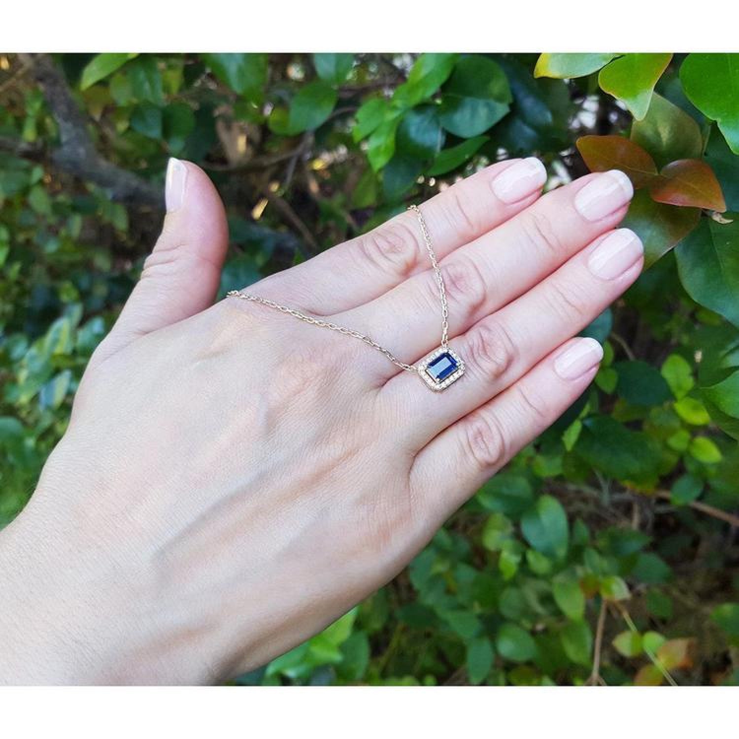 1.03 ct. natural blue sapphire, emerald cut, east-west necklace with diamond halo in 14K yellow gold.