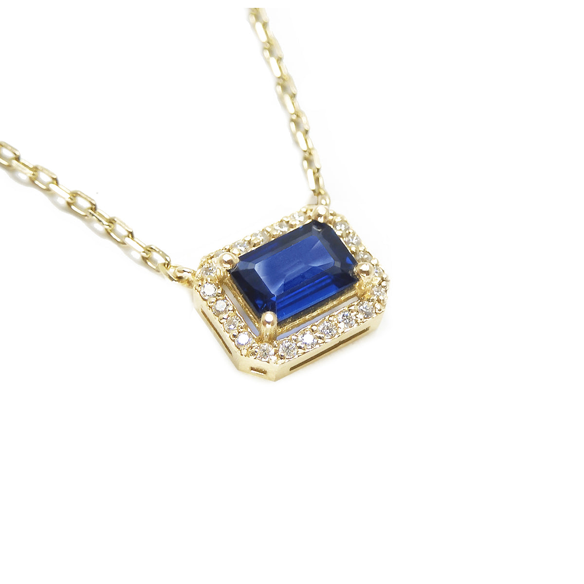 Right side top view of a natural blue sapphire necklace emerald cut halo diamonds in 14k yellow gold.