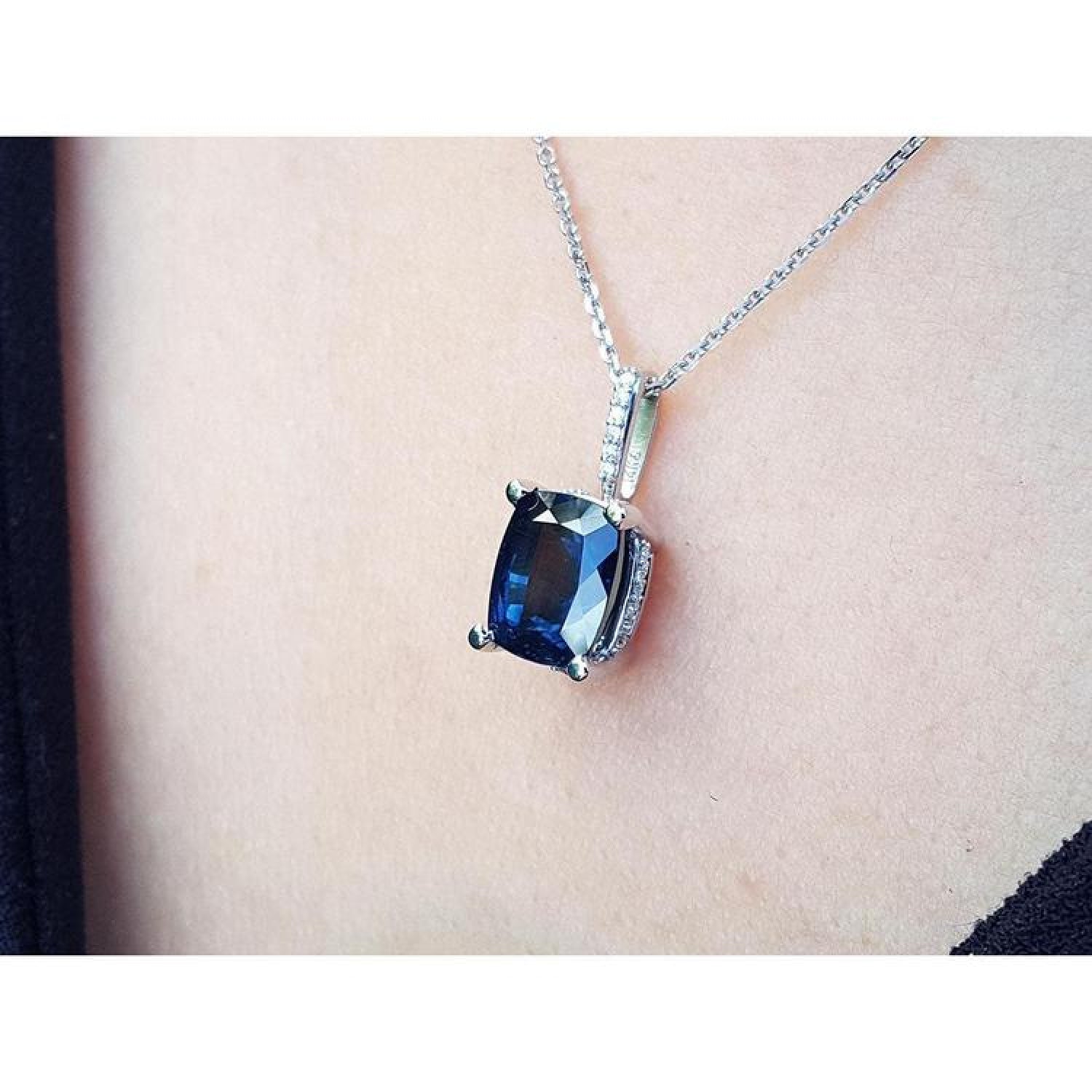4.11 ct deep blue cushion cut sapphire pendant in 14K white gold, worn on a neck.